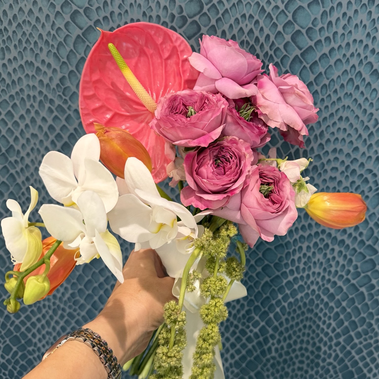 Colorful bridal bouquet with pink roses, anthurium, orchids and orange tulips by Petite Petal