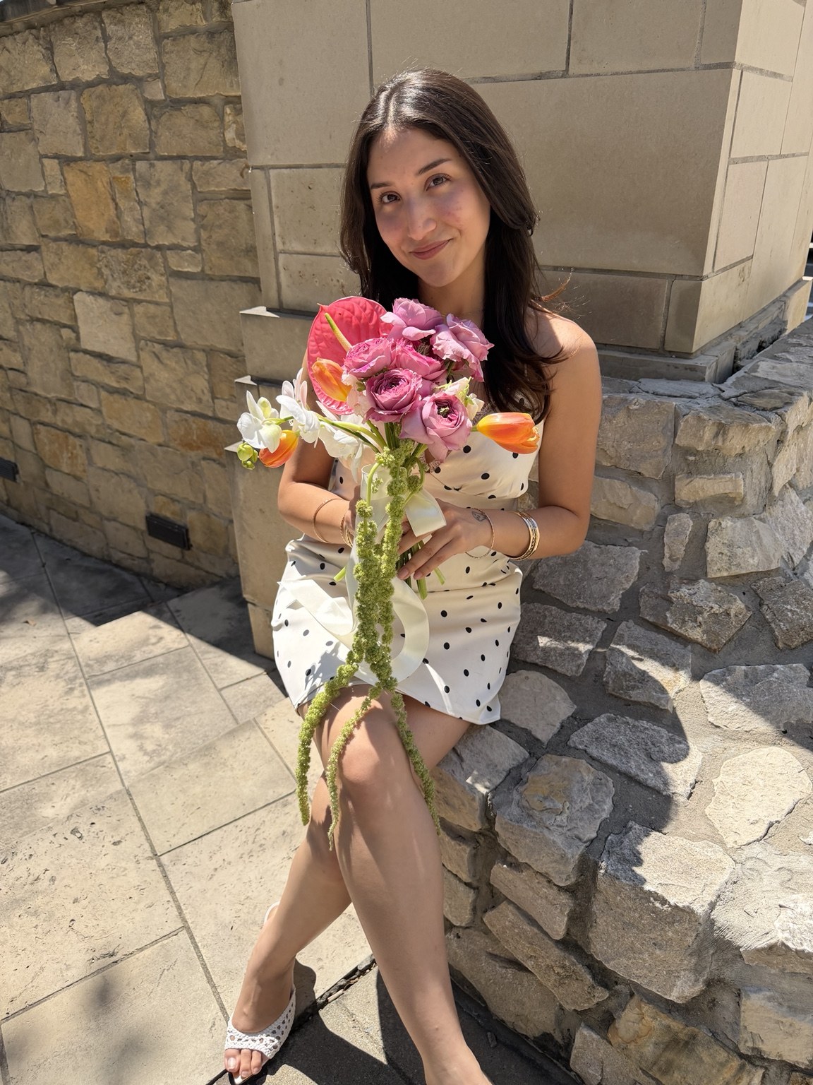 Bride holding a colorful Petite Petal bouquet with pink roses, orchids and orange tulips