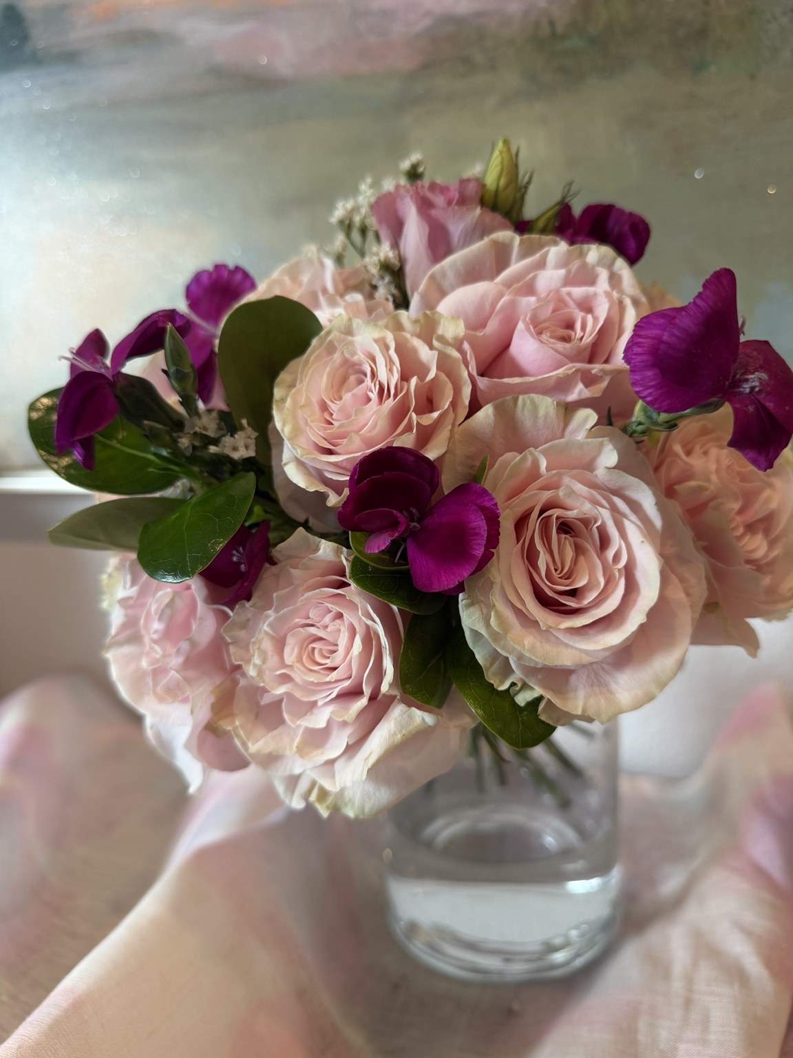 Soft pink rose arrangement with purple sweet peas and greenery by Petite Petal